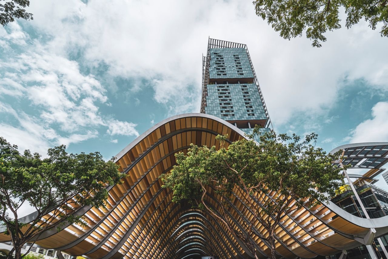 Architectural elegance featuring a towering skyscraper and a wave-like structure under the clear sky.
